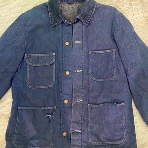 May include: A dark blue denim work jacket with multiple pockets and brass buttons. The jacket has a corduroy collar and a lined interior.