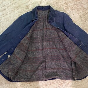 May include: A blue denim jacket with a plaid flannel lining. The jacket has a button-up closure and two pockets on the front.