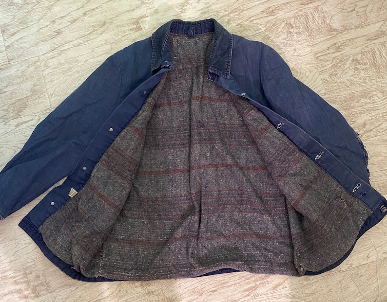 May include: A blue denim jacket with a plaid flannel lining. The jacket has a button-up closure and two pockets on the front.
