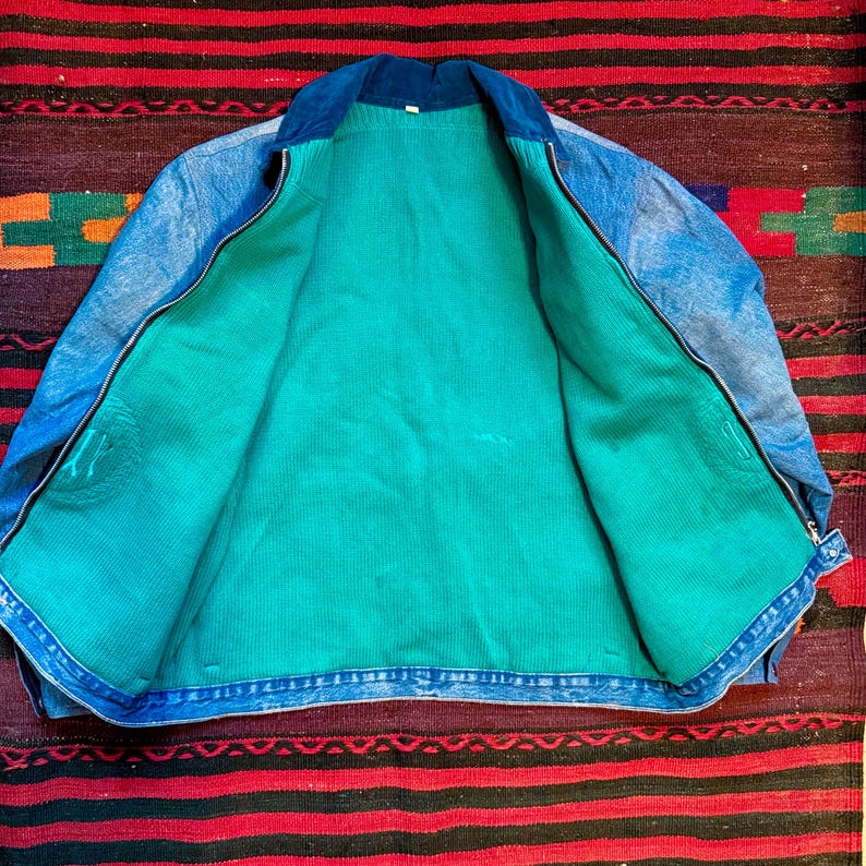 K&ouml;nnte beinhalten: Eine blaue Jeansjacke mit einem tealgr&uuml;nen Futter. Die Jacke hat einen Rei&szlig;verschluss und einen Cordkragen.