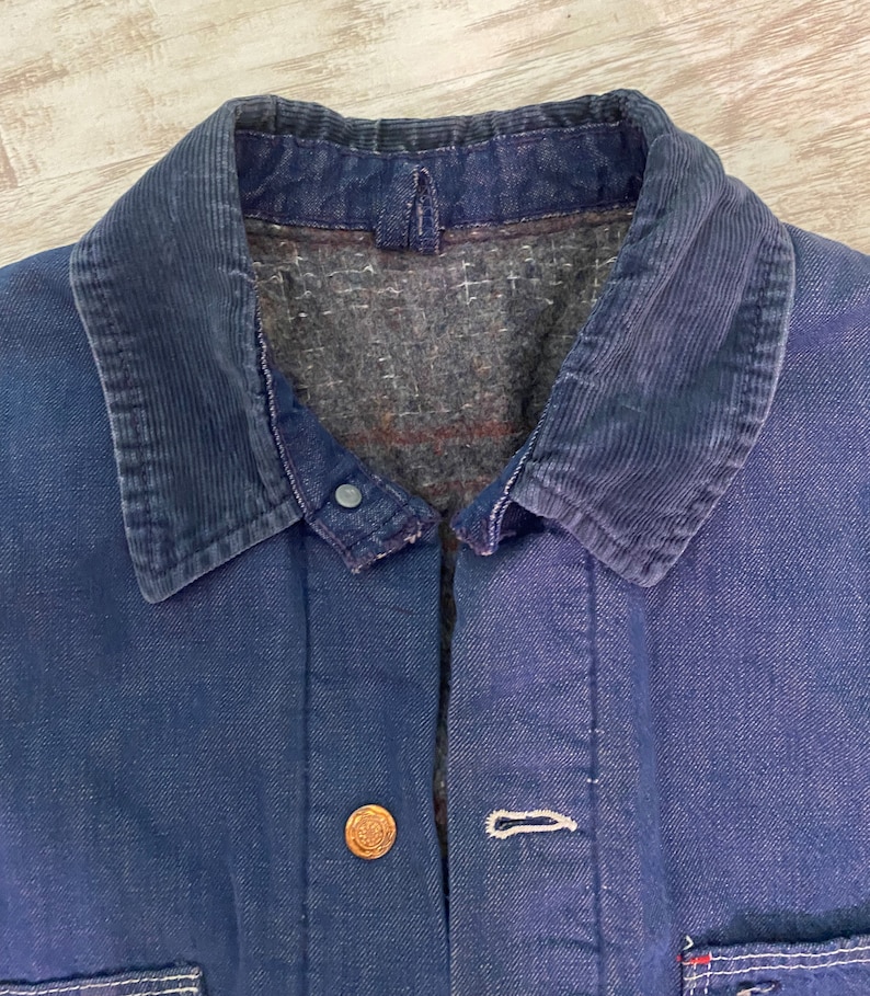 May include: A dark blue denim jacket with a corduroy collar. The jacket has a button closure and two pockets on the front.