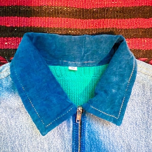 K&ouml;nnte beinhalten: Eine blaue Jeansjacke mit einem blauen Cordkragen und einem gr&uuml;nen Strickfutter. Die Jacke hat einen Rei&szlig;verschluss und eine Tasche auf der linken unteren Seite.