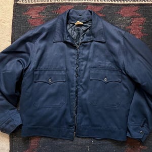 May include: A navy blue jacket with a collared neckline and a zipper closure. The jacket features two chest pockets and two side pockets. The jacket is made of a smooth, durable fabric and has a quilted lining.