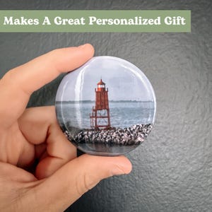 Pu&ograve; includere: Un faro rosso e bianco su una costa rocciosa con un'estensione d'acqua sullo sfondo. Il faro &egrave; una destinazione turistica popolare e costituisce un ottimo regalo personalizzato.