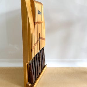May include: A wooden knife block with a light brown finish and a black label that says "Waring-Rex" holds a set of knives with brown handles.