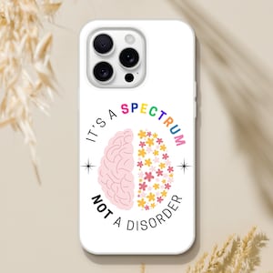 Puede incluir: Carcasa de teléfono blanca con un diseño de cerebro rosa y el texto "It's a spectrum not a disorder" en arcoíris.