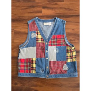 May include: A sleeveless denim vest featuring a patchwork design of blue denim, red and yellow plaid fabric, and gray panels. The vest has a V-neckline, a front button closure with silver-toned buttons, and white embroidered heart and flower motifs.