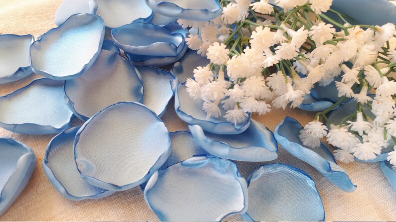 May include: A scattering of light blue satin rose petals, perfect for wedding decor or special events.