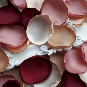 May include: Assortment of silk rose petals in various shades of pink, peach, and burgundy. The petals are arranged in a random pattern, creating a visually appealing display.