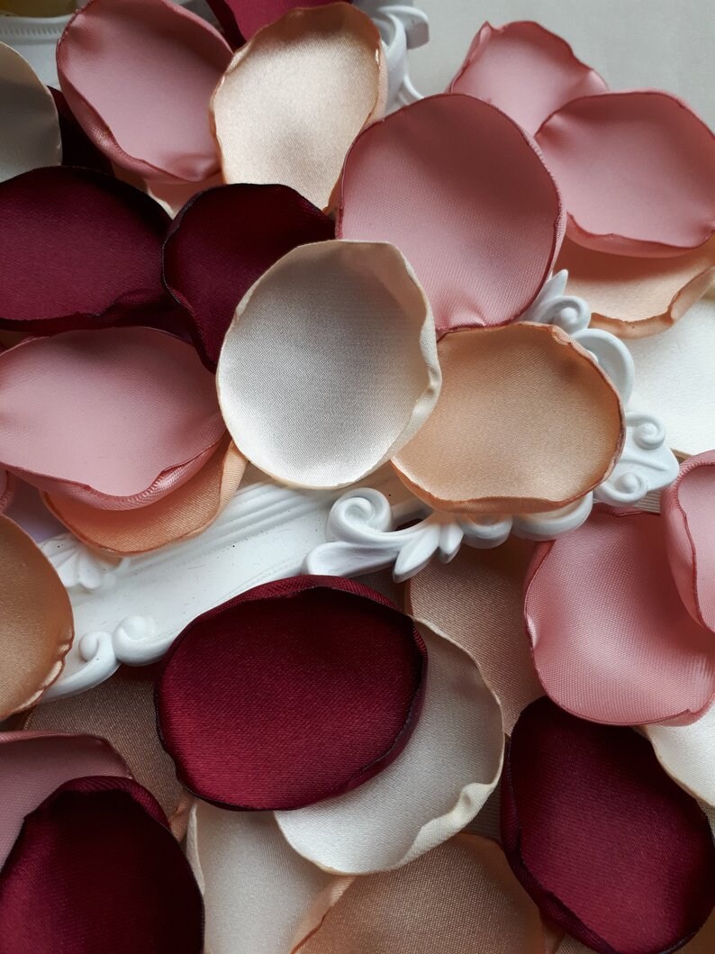 May include: Assortment of silk rose petals in various shades of pink, peach, and burgundy. The petals are arranged in a random pattern, creating a visually appealing display.