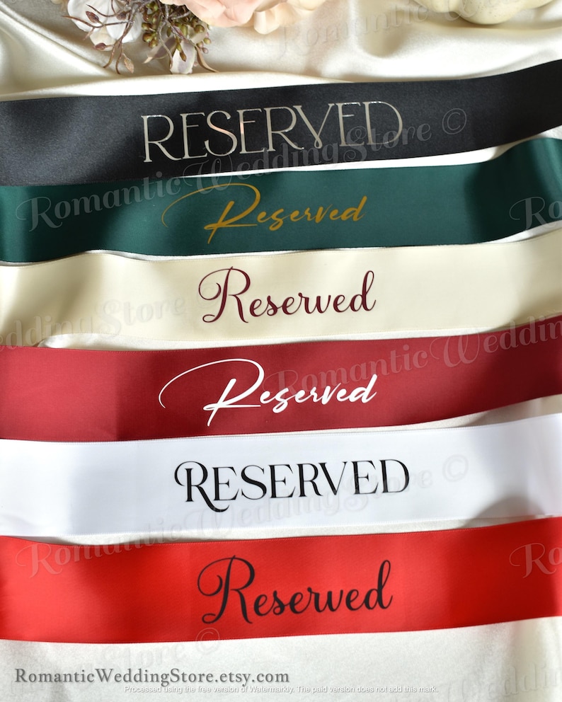 May include: A collection of six satin ribbons in black, dark green, cream, burgundy, white, and red. Each ribbon features the word Reserved printed in a distinct font style, including serif, script, and elegant lettering, arranged horizontally.