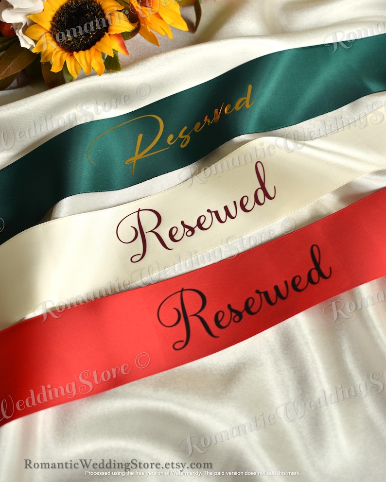 May include: Three satin ribbons in dark green, cream, and red, each featuring the word Reserved printed in a cursive script. The green ribbon has gold text, the cream ribbon has dark red text, and the red ribbon has black text.