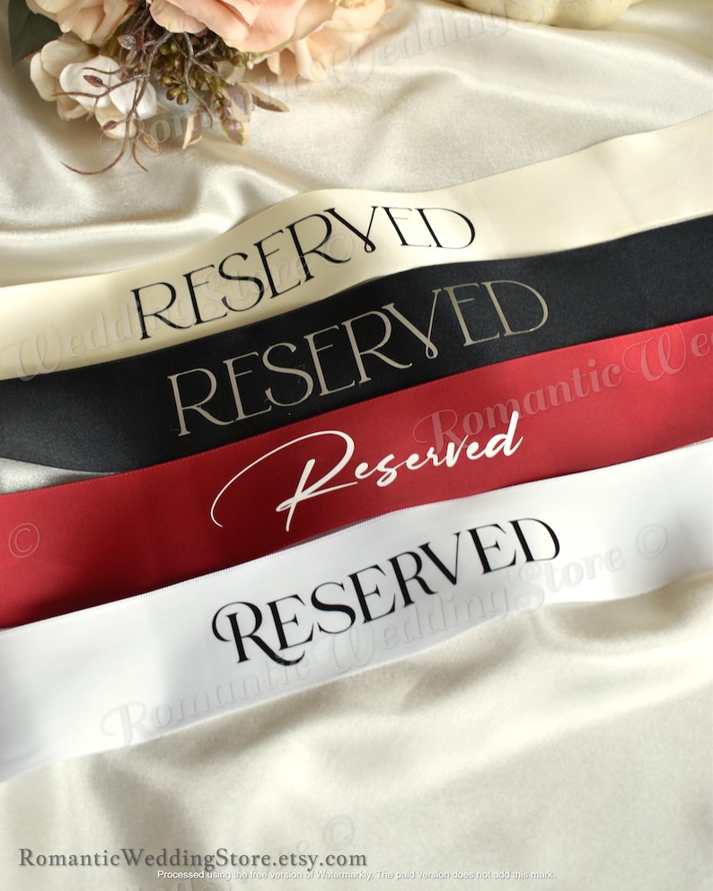 May include: Four satin sashes in cream, black, dark red, and white. The top three sashes feature the word RESERVED in a black serif font, while the third sash displays the word Reserved in a white script font. The bottom sash has RESERVED in black.