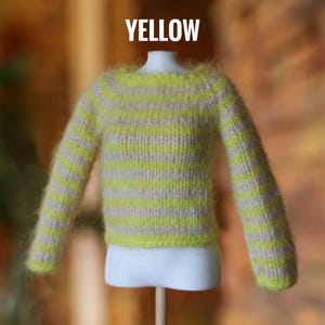 May include: A miniature yellow and beige striped sweater. The sweater has long sleeves and a crew neck. The word "YELLOW" is displayed in white block letters above the sweater.