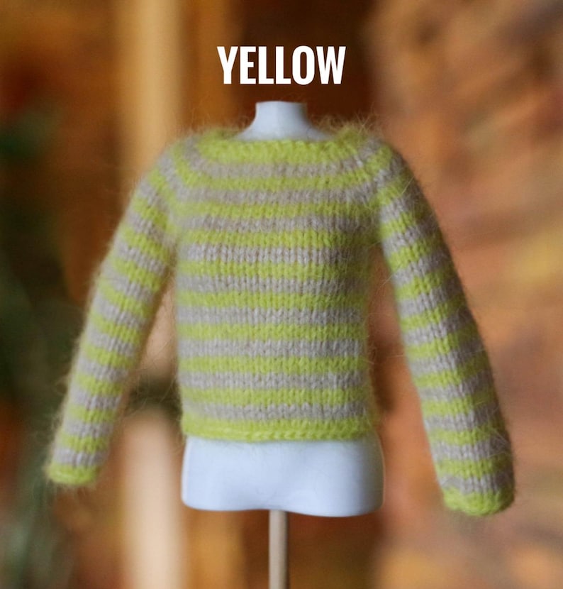 May include: A miniature yellow and beige striped sweater. The sweater has long sleeves and a crew neck. The word "YELLOW" is displayed in white block letters above the sweater.