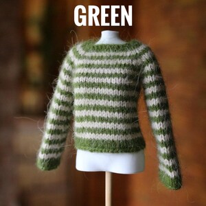 May include: A miniature green and white striped sweater. The sweater is displayed on a white mannequin and has long sleeves. The word "GREEN" is printed in white at the top of the image.
