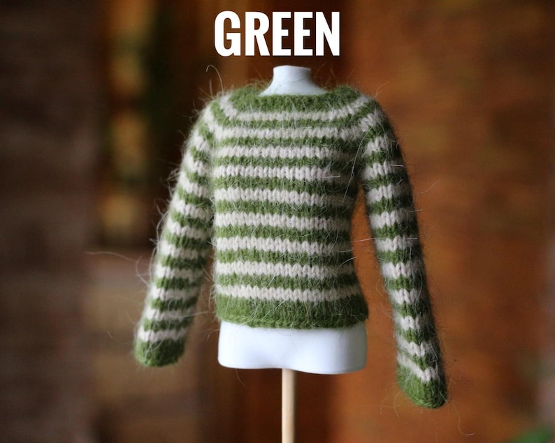 May include: A miniature green and white striped sweater. The sweater is displayed on a white mannequin and has long sleeves. The word "GREEN" is printed in white at the top of the image.