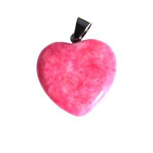May include: A heart-shaped pendant with a vibrant pink hue. The pendant has a polished surface and a silver-colored bail for attaching to a chain. The pink color has a marbled effect.