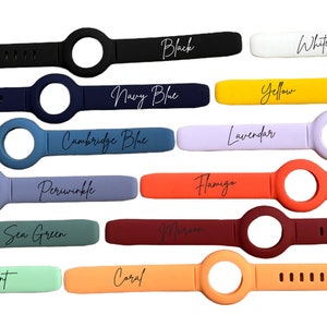 K&ouml;nnte beinhalten: Ein Set mit 14 Silikon-Uhrenarmb&auml;ndern in verschiedenen Farben, darunter Schwarz, Wei&szlig;, Marineblau, Gelb, Cambridge-Blau, Lavendel, Periwinkle, Flamingo, Seegr&uuml;n, Minze, Koralle und Orange. Jedes Armband hat eine kreisf&ouml;rmige &Ouml;ffnung f&uuml;r ein Zifferblatt.