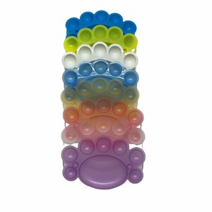 May include: A stack of rainbow colored silicone fidget toys. Each toy is shaped like a half circle with a row of bubbles. The toys are stacked from blue to purple.