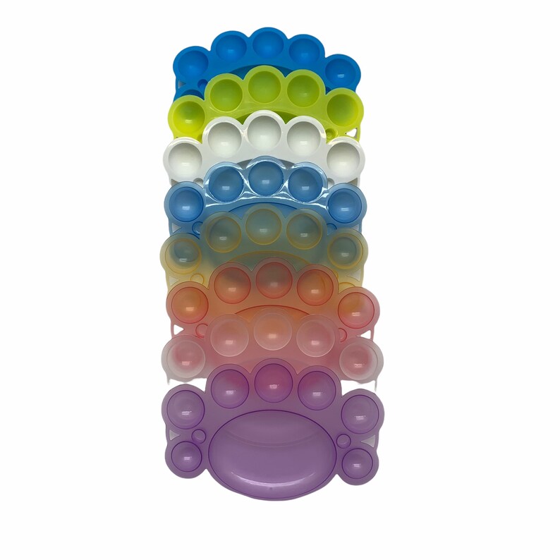 May include: A stack of rainbow colored silicone fidget toys. Each toy is shaped like a half circle with a row of bubbles. The toys are stacked from blue to purple.