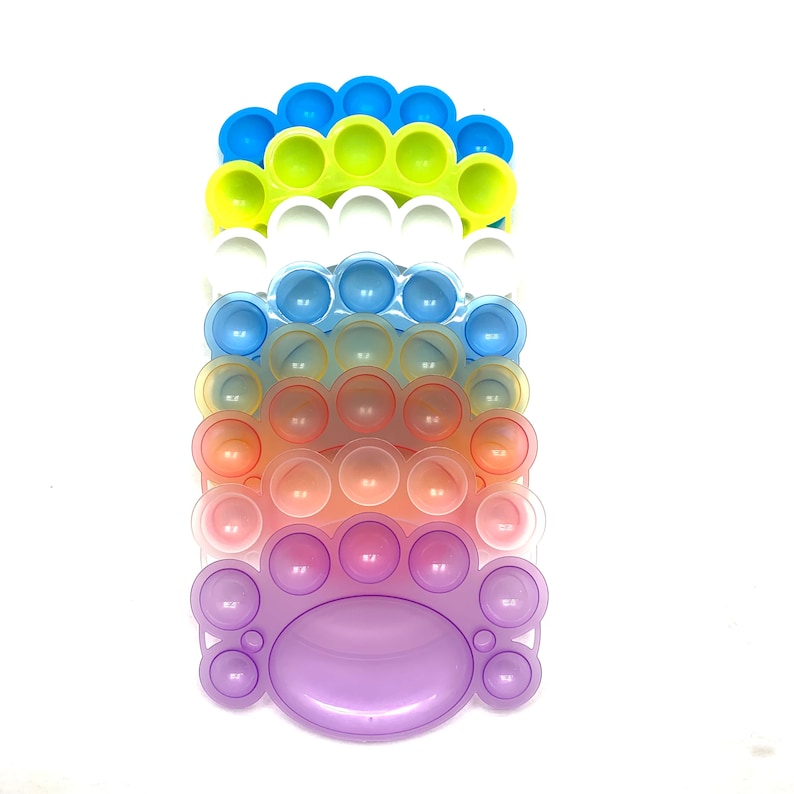 May include: A set of five rainbow colored pop it fidget toys. The toys are stacked on top of each other, with the largest toy at the bottom and the smallest toy at the top. The toys are made of silicone and have a variety of colors, including purple, pink, orange, blue, and yellow.