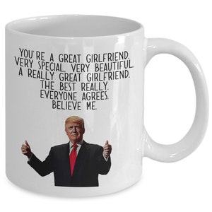 May include: White ceramic coffee mug with a black and white image of a man with a thumbs up gesture. The text on the mug reads: "You're a great girlfriend. Very special. Very beautiful. A really great girlfriend. The best really. Everyone agrees. Believe me."
