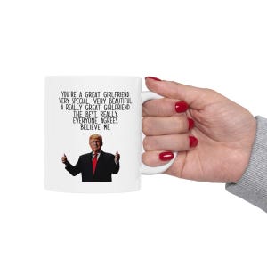 May include: White ceramic mug with a black and white image of a man in a suit and red tie. The text on the mug reads "You're a great girlfriend. Very special. Very beautiful. A really great girlfriend. The best really. Everyone agrees. Believe me."