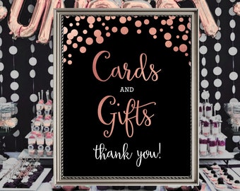 May include: A black framed sign with rose gold confetti and text that reads "Cards and Gifts thank you!"