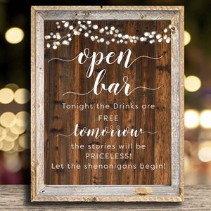 Puede incluir: Cartel de madera con las palabras "open bar" en escritura elegante. El cartel tiene un fondo de vetas de madera rústica y un marco gris desgastado. El texto adicional dice "Tonight the Drinks are FREE tomorrow the stories will be PRICELESS! Let the shenanigans begin!"