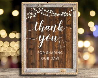 May include: Rustic wooden sign with a white frame and string lights. The sign says "Thank you for sharing our day!" with a heart.