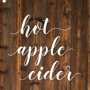Puede incluir: Un fondo de madera r&uacute;stico con una cadena de luces blancas colgando en la parte superior. Las palabras "hot apple cider" est&aacute;n escritas en cursiva blanca.