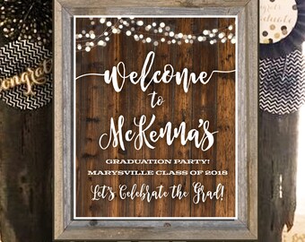 Può includere: Un cartello in legno rustico con testo bianco che recita "Benvenuti alla festa di laurea di McKenna! Classe di Marysville del 2018 Festeggiamo la laurea!"