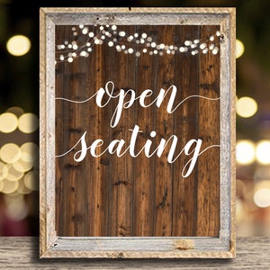 May include: A rustic wooden sign with a white distressed frame and string lights. The sign reads "open seating" in white cursive lettering.