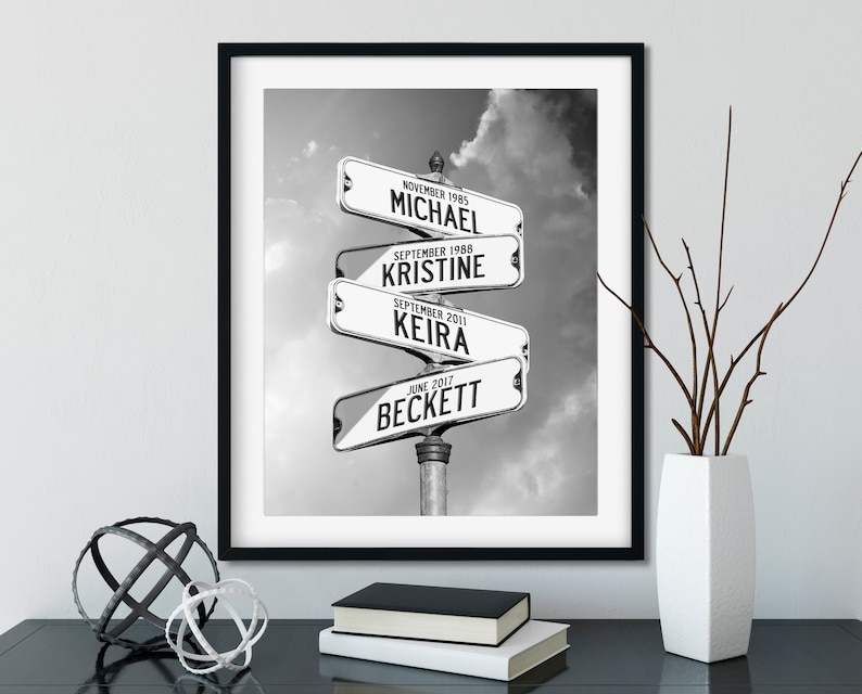 May include: Black and white photo of four street signs with names and dates. The signs are arranged in a circle and point in different directions. The signs read: "November 1985 Michael", "September 1988 Kristine", "September 2011 Keira", and "June 2017 Beckett".