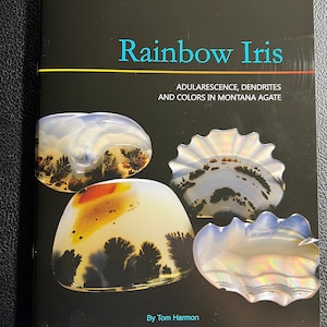 May include: Book cover titled "Rainbow Iris:  Adularescence, Dendrites and Colors in Montana Agate" by Tom Harmon. The cover features four agate stones with various colors and patterns.