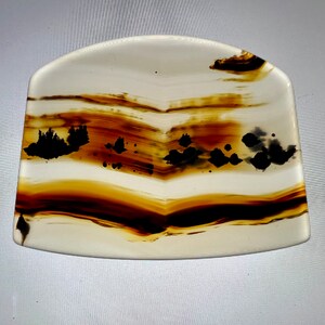 Può includere: Una lastra di agata bianca, marrone e nera con una forma curva e un motivo a bande. L'agata ha una finitura naturale e lucida.