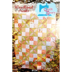 May include: A colorful quilt with a patchwork design featuring squares and leaf-like shapes. The quilt has a green, orange, and white color scheme with the words "Woodland Trails" and "Quilt Story" on the top. The number "#134" is at the bottom.