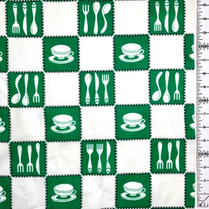 May include: White and green checkered fabric with a repeating pattern of kitchen utensils and teacups. The design features white forks, spoons, knives, and teacups on a green background, stitched with black thread, alternating with white squares.