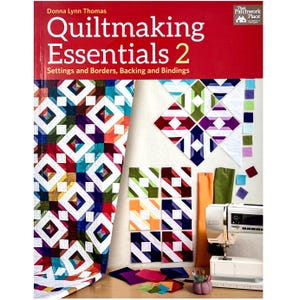 May include: A book titled "Quiltmaking Essentials 2" with the subtitle "Settings and Borders, Backing and Bindings." The image shows a colorful quilt, fabric squares, and a sewing machine. The quilt features a geometric pattern with red, blue, green, and white squares.