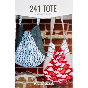 May include: A sewing pattern cover titled 241 TOTE a fabric lover's favorite featuring two tote bags. The left bag has a blue and black triangle print with dark gray side panels. The right bag has a red cloud print with light gray side panels.
