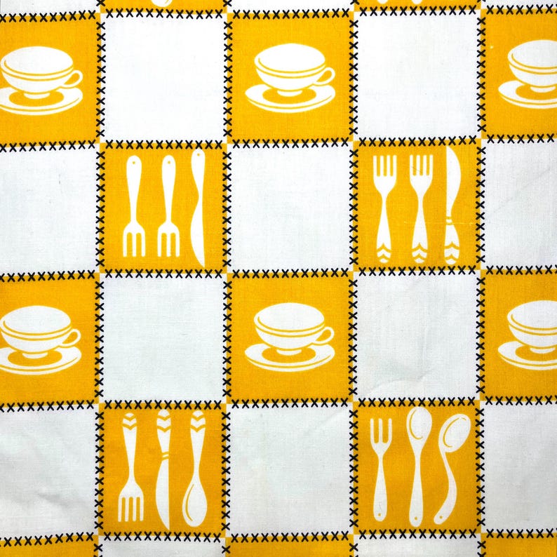 May include: A white and yellow checkered pattern fabric featuring repeating images of teacups, forks, knives, and spoons. The fabric has a stitched border and is suitable for kitchen or dining decor.