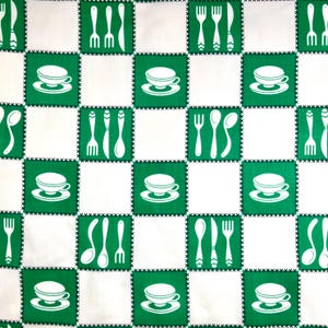 May include: A white and green checkered pattern fabric featuring alternating squares. Green squares display white teacups, forks, spoons, and knives. The fabric has a stitched border, creating a vintage, retro aesthetic.