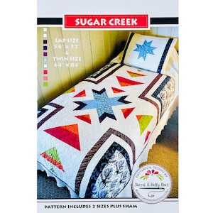 May include: A quilt pattern with the text "SUGAR CREEK". The quilt features a starburst design with blue, orange, and red geometric shapes. The pattern includes lap size 56" x 72" and twin size 64" x 84" options, plus a sham.