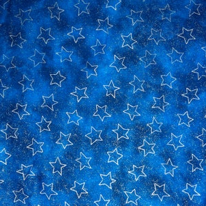 May include: A close-up of a blue fabric with a pattern of white stars. The stars are outlined and scattered across the surface. The background has a mottled appearance, with lighter and darker shades of blue.