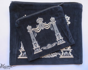 May include: Two black velvet bags with gold embroidered decorative designs. The larger bag has a zipper closure. The embroidery features crowns, columns, and ornate scrollwork. The smaller bag is placed on top of the larger one.
