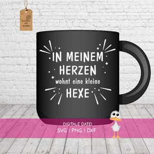Könnte beinhalten: Ein schwarzer Keramikbecher mit dem weißen Text IN MEINEM HERZEN wohnt eine kleine HEXE, umgeben von kleinen Stern- und Strichgrafiken. Unter dem Becher steht der Text DIGITALE DATEI SVG | PNG | DXF, begleitet von einer kleinen Ente.