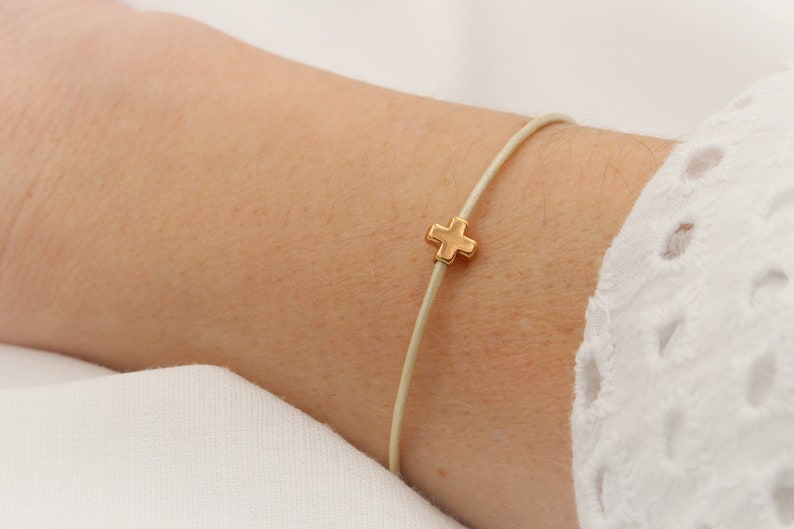 Lederarmband in creme mit Kreuz rosegold am Handgelenk getragen