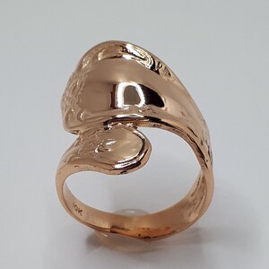 May include: A gold-toned ring with a unique, wave-like design. The ring is marked with "10K" on the inside band.