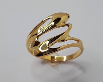 Op de afbeelding: Een gouden ring met een uniek, abstract ontwerp. De ring is gemaakt van glad, glanzend metaal en heeft een moderne, minimalistische stijl.